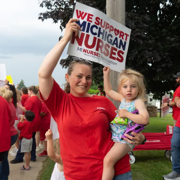 A nurse holding a sign and a toddler